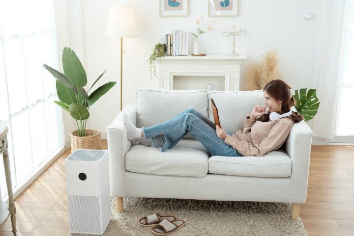 Air purifier running in a bright living room, used for CADR sizing calculations