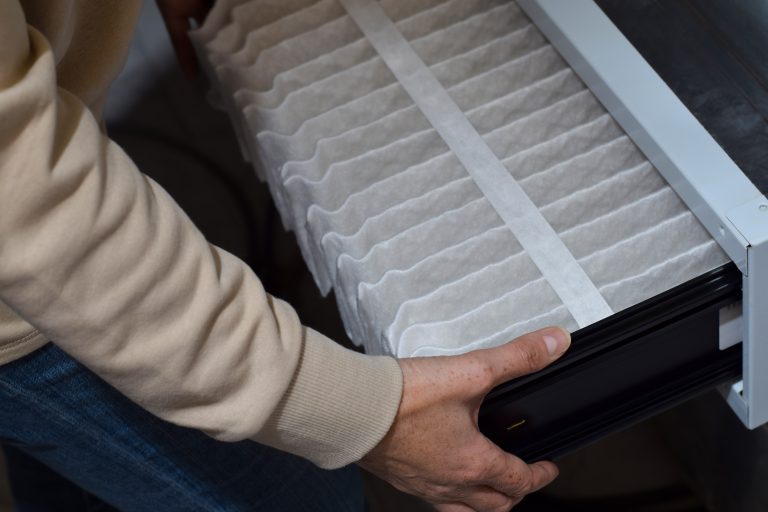 Hands replacing a pleated air filter