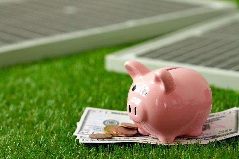 Solar panel model and piggy bank representing energy cost savings